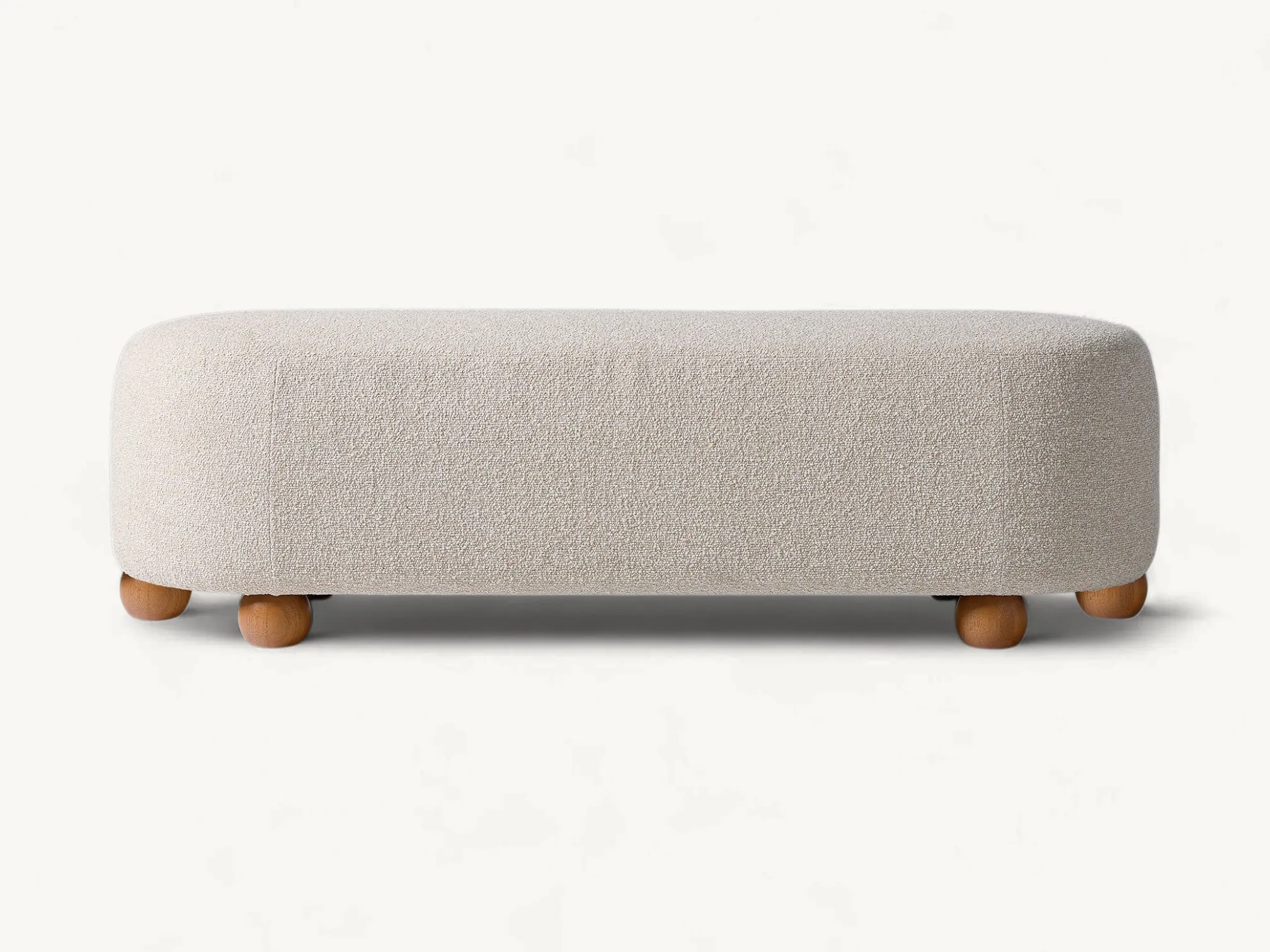 Upholstered long bench with rounded edges and solid teak wood spherical legs in a neutral cream fabric.