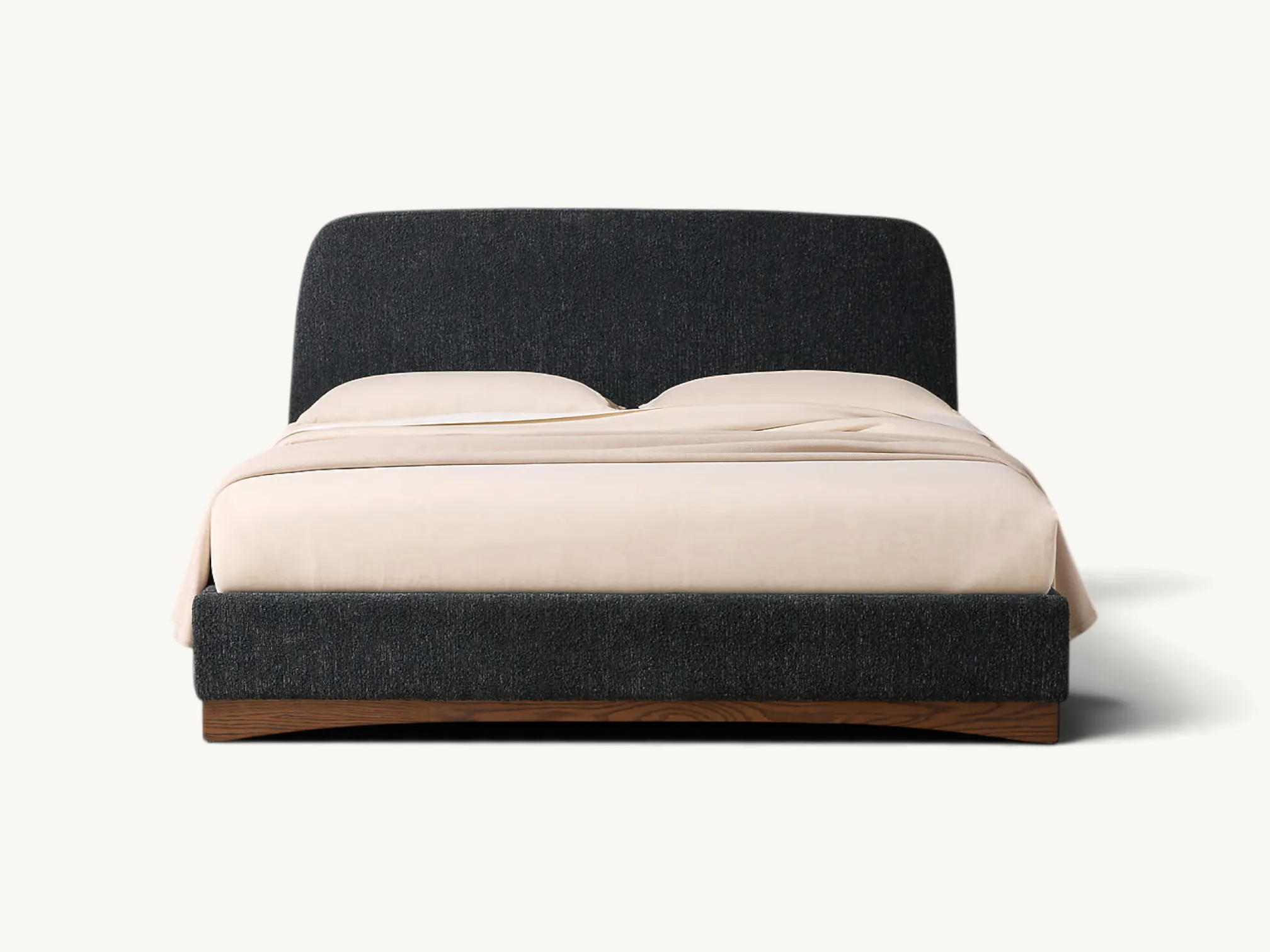 Low-profile upholstered platform bed in textured charcoal gray fabric, featuring a rounded rectangular headboard and a warm brown wooden plinth base with a subtle arched bottom edge.