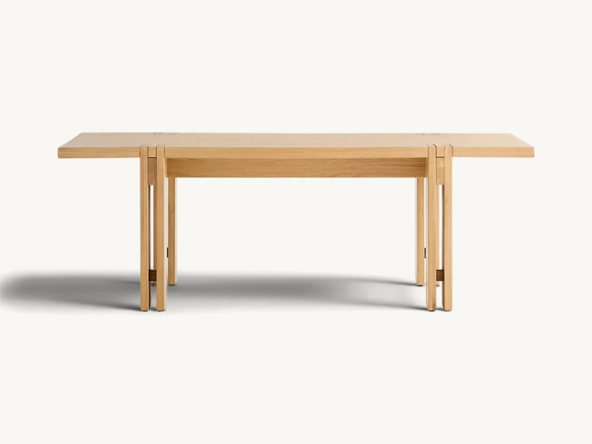 Rectangular natural light oak wood dining table featuring unique split-leg joinery exposed through the smooth tabletop