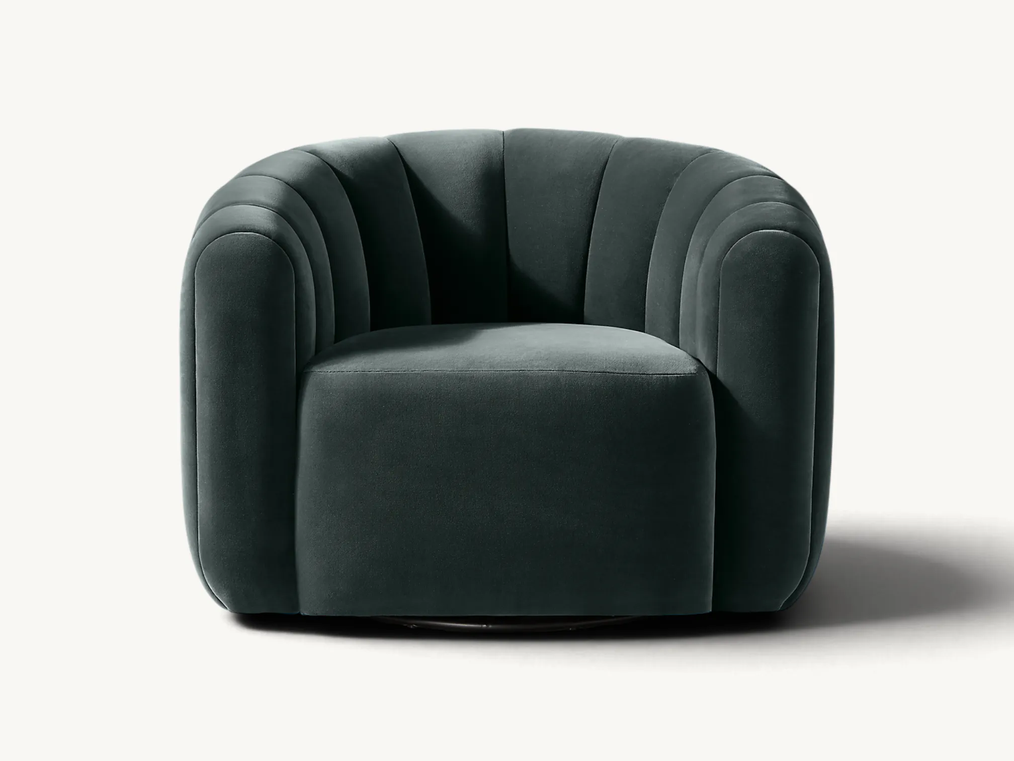 Dark green velvet channel-tufted swivel armchair with a rounded barrel silhouette in an interior setting