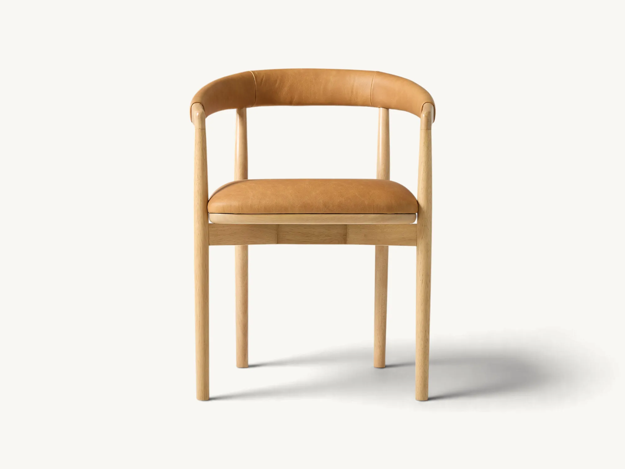 Japandi style dining chair made of light solid teak with tan leather seat and curved backrest.