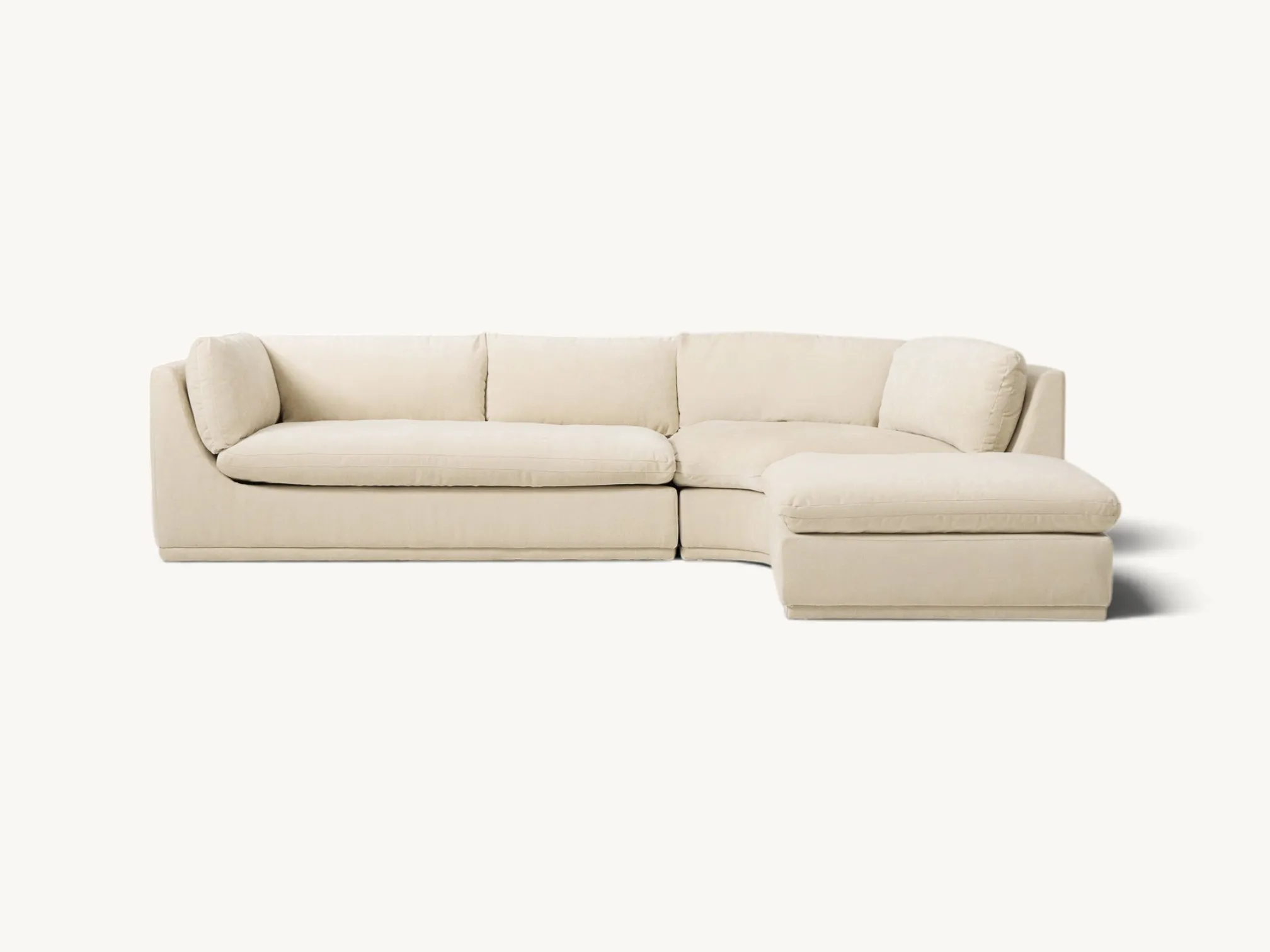 Modern cream three-piece curved sectional sofa with deep cushions and an integrated ottoman section in a living room