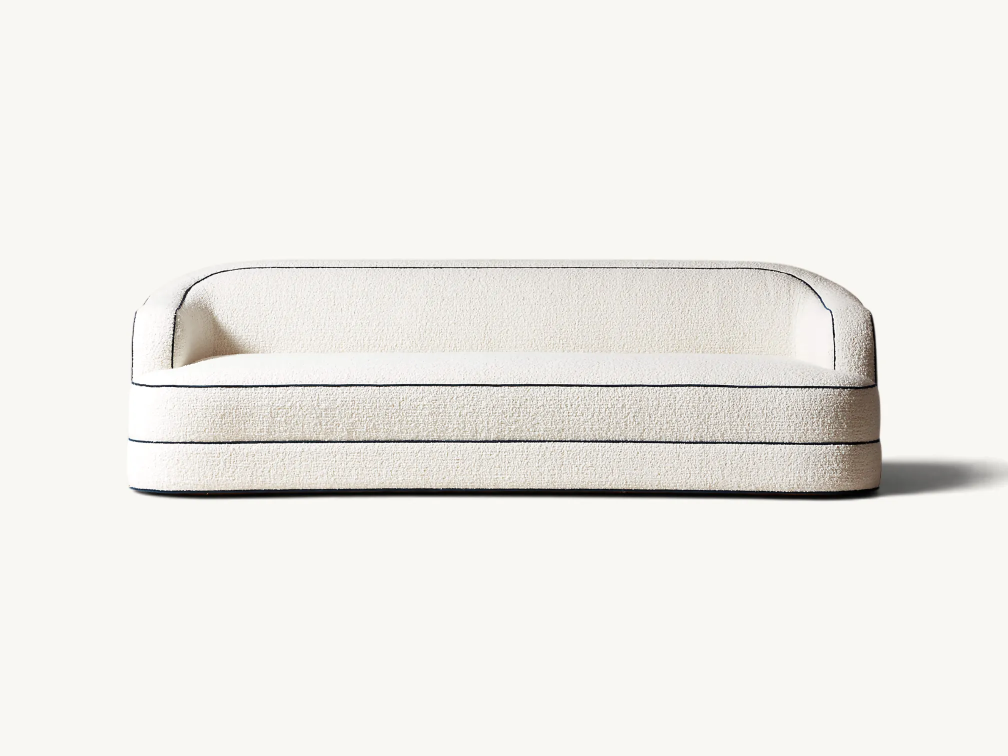 Curved cream bouclé sofa with black contrast piping and a sculptural tiered base.