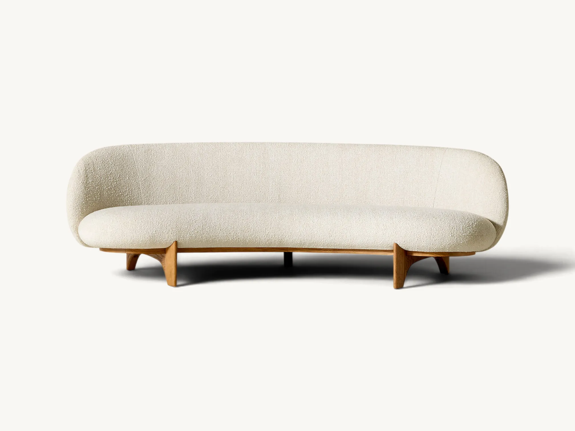 Curved cream bouclé sofa with an organic silhouette and a low-profile teak wood frame base.