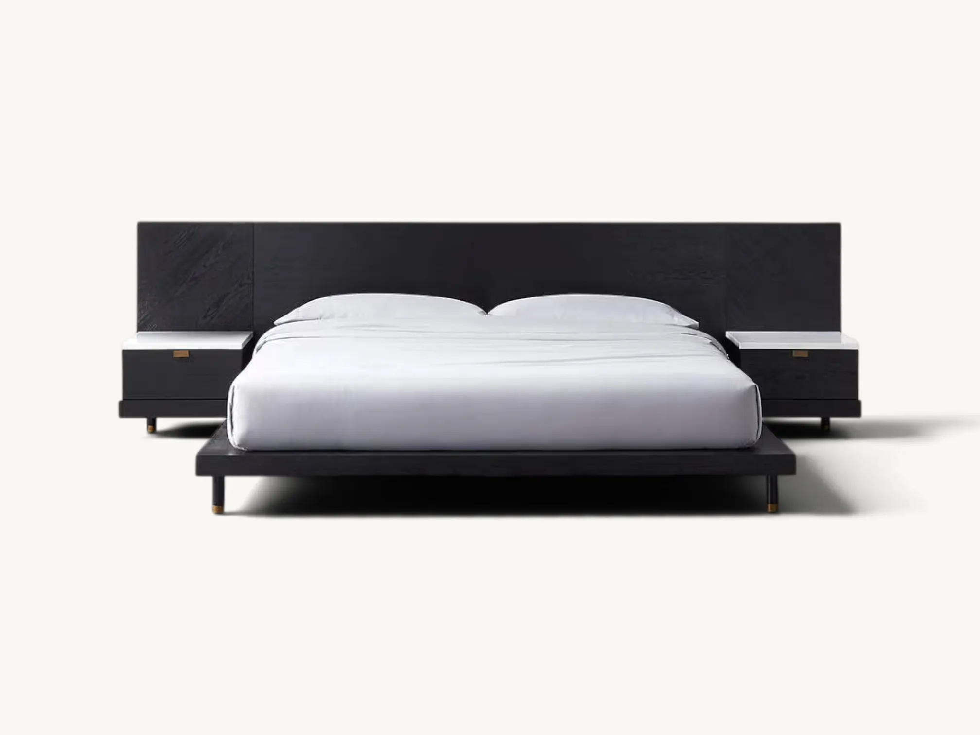 Low-profile black wooden modern platform bed with an extended wide headboard, integrated single-drawer floating nightstands featuring white marble tops, and slender cylindrical legs with brass feet.