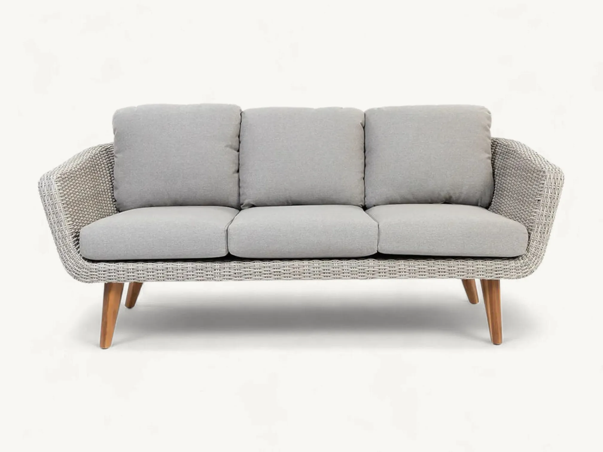 Organic curved outdoor sofa made of full natural rattan with plush cream cushions.