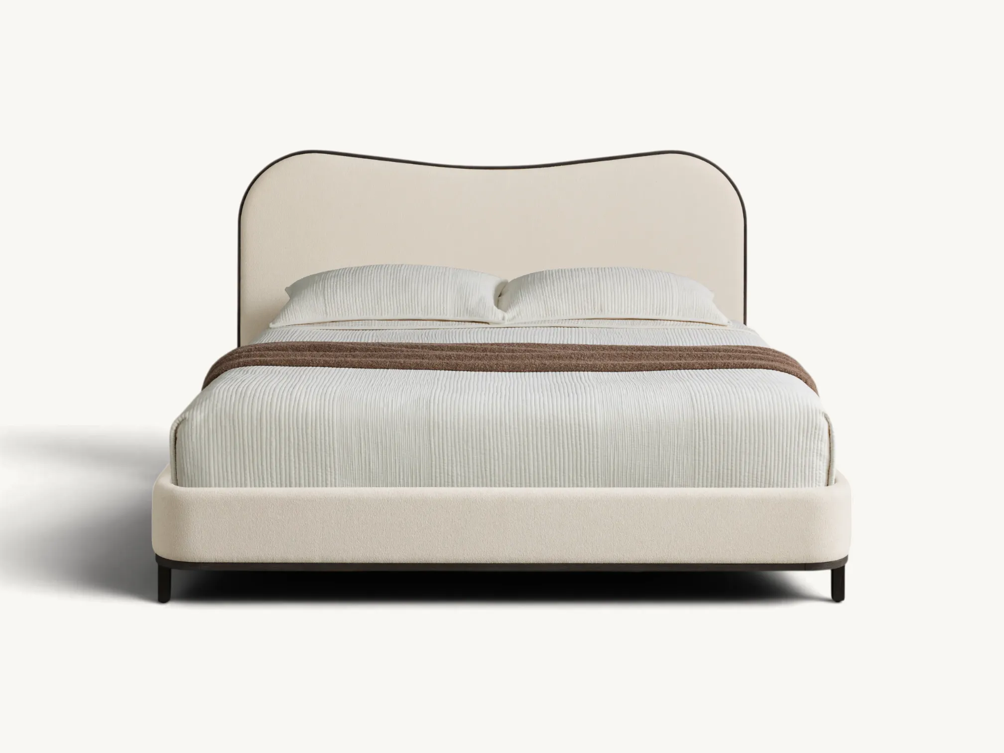 Modern upholstered bed frame with wavy contoured headboard, dark teak wood trim, slim legs, and minimalist cream fabric design.