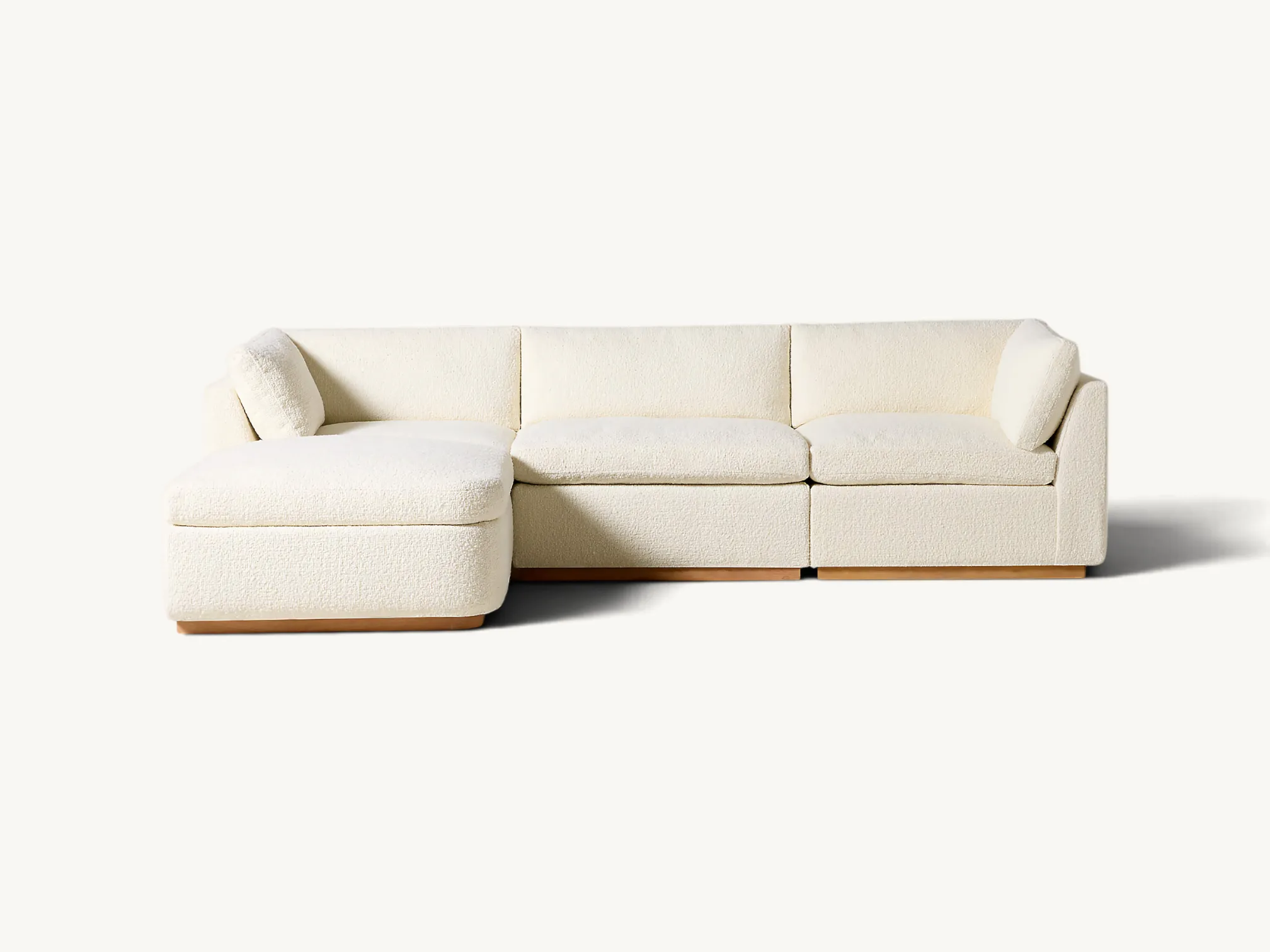 Modern four-piece modular sectional sofa with an integrated chaise lounge, ivory textured upholstery, and a low-profile solid teak wood base.