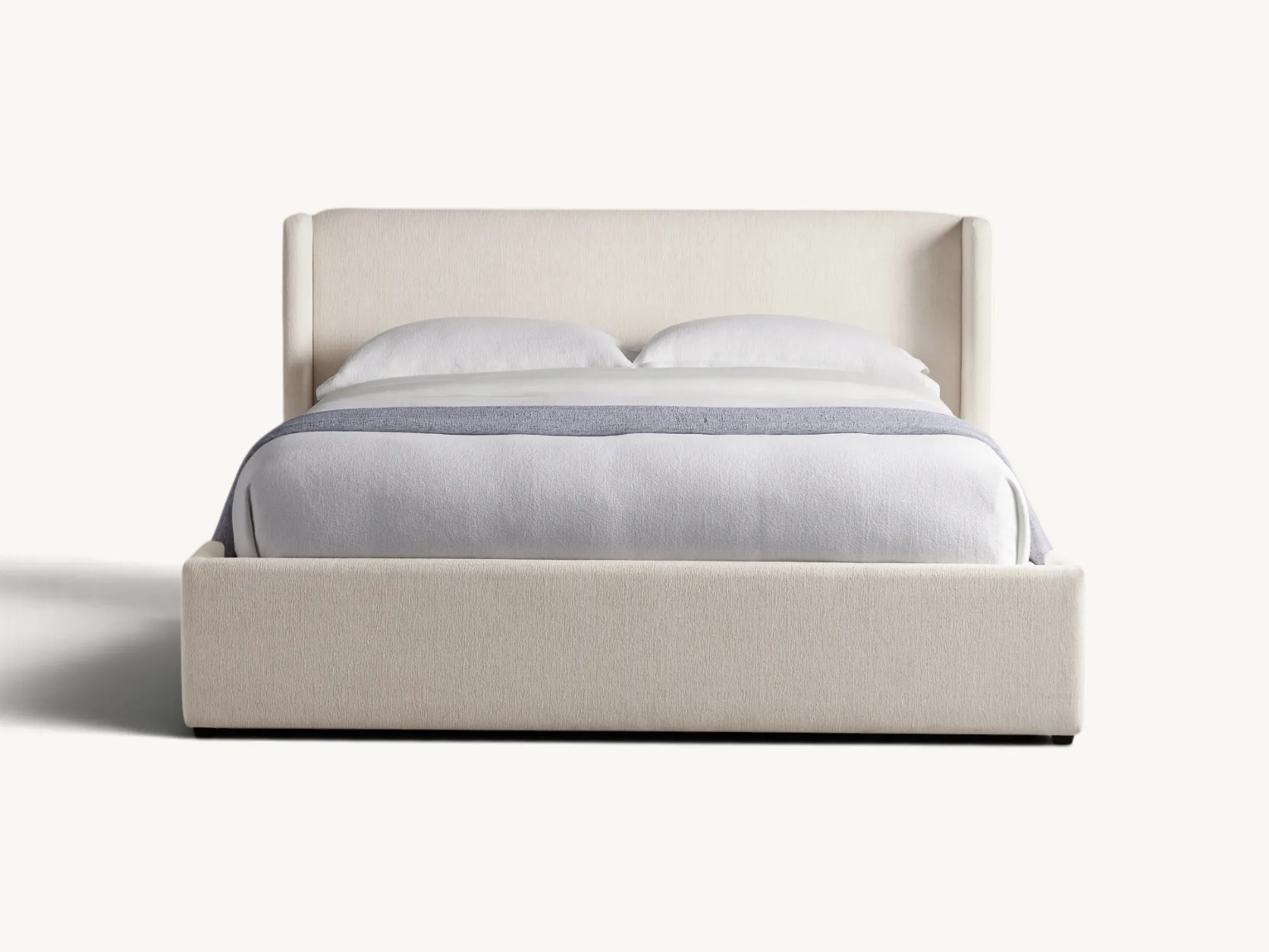Modern fully upholstered teak wood bed frame with cream textured fabric and wingback headboard.