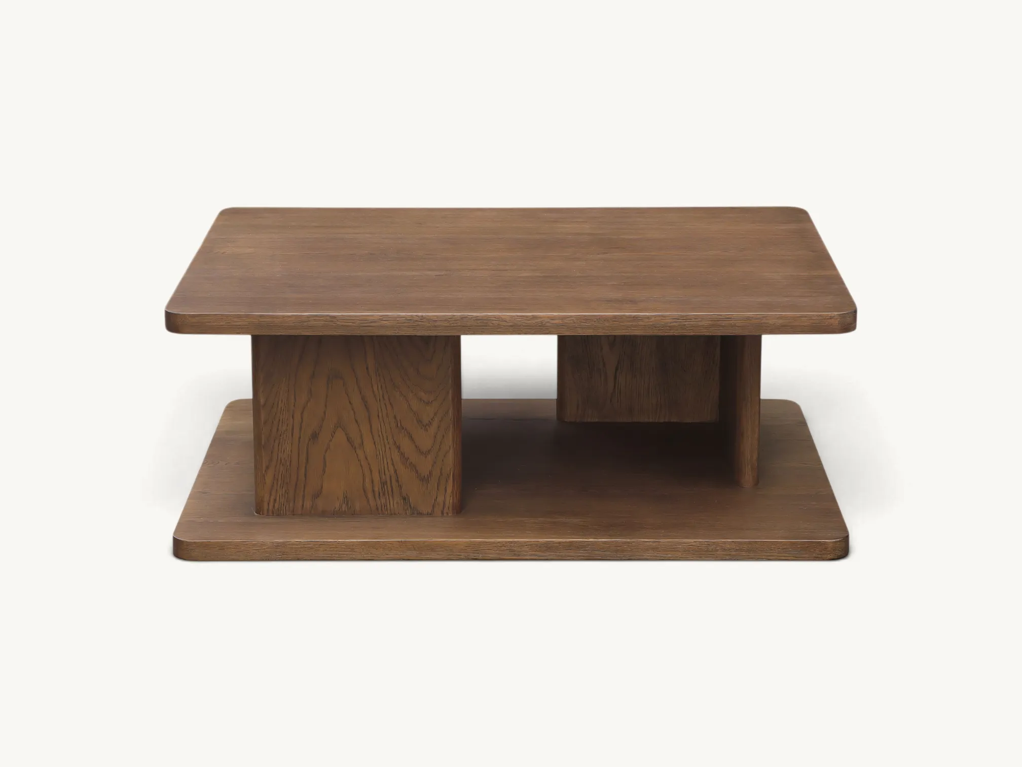 Modern tiered teak wood coffee table with a central block pedestal and open side storage compartments on a white background.